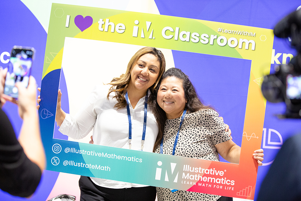 IMpact Share Your Story Two women posing for a photo, holding a prop frame that reads: I love the IM Classroom